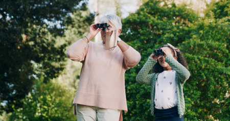 Grandma, child and binocular in park for travel, sightseeing and search for view with bonding. Old...
