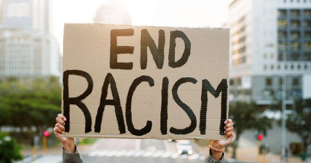 Hands, racism protest and poster in city for inclusion, human rights and equality with peace in road. Person, activist and race relations rally with sign, announcement and call to action in townの写真素材