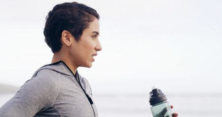Fitness, water bottle and woman by ocean for exercise, training and cardio workout in nature. Space,...