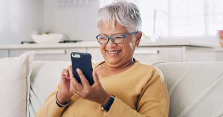 Senior woman, phone and smile on sofa for typing message, reading ebook or search online news....