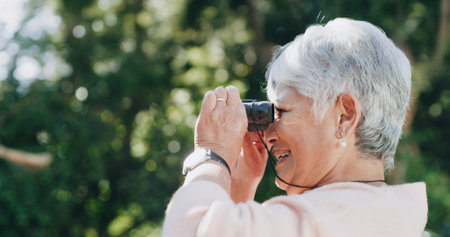 Smile, senior woman and binocular outdoor for travel, bird watching and holiday sightseeing. Happy, elderly person and nature observation with equipment, wildlife study and view of vacation discoveryの写真素材