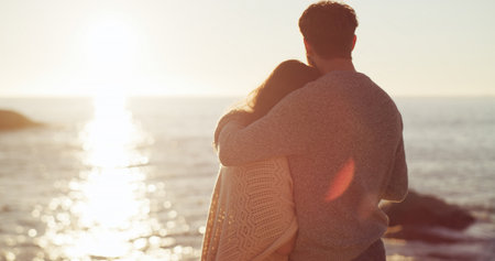 Space, sunset and couple hug at beach for honeymoon, valentines day and love in relationship together. Sea, relax and back view of people bonding on holiday for romantic anniversary, vacation or dateの写真素材