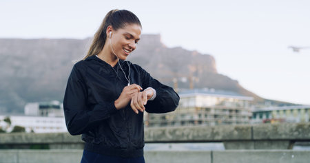 Woman, runner and smile with smart watch in city with timer, stats or earphones for music with...