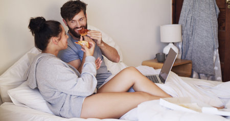 Food, laptop and couple with pizza on bed watching movie, series or show together on weekend. Happy,...