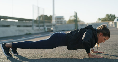Woman, push up and exercise in street for fitness, challenge and routine for wellness on bridge. Person, outdoor and workout in city with muscle development, health or training on ground in Spainの写真素材