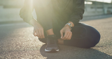 Hands, runner and tie shoelaces in city, bridge and reflection with fitness routine in morning. Person, athlete and feet for training in street, exercise and start workout for wellness in townの写真素材