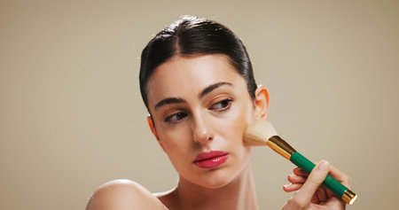 Beauty, makeup and brush with woman in studio for blush, cosmetics and foundation application....