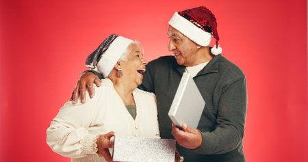 Gift box, christmas and senior couple in studio with festive, holiday or marriage tradition....