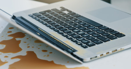 Laptop, coffee and spill liquid in office for accident, work chaos and keyboard damage. Takeaway, pc and messed drink on tech with clumsy problem, electronic insurance and hazard of beverage disasterの写真素材