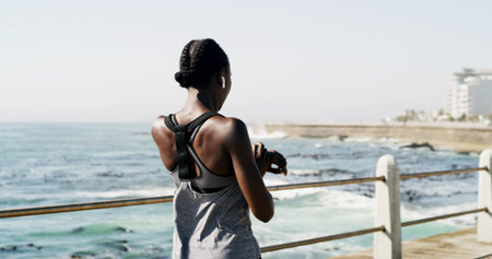 Black woman, back or fitness with watch on ocean coast for sport app, time or workout schedule....