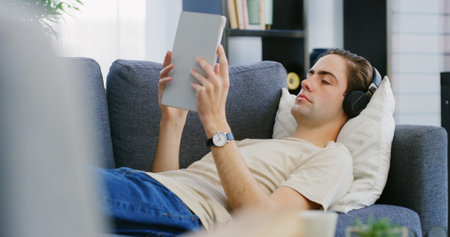 Man, headphones and tablet on couch for relax, streaming media and entertainment app. Chill, music...