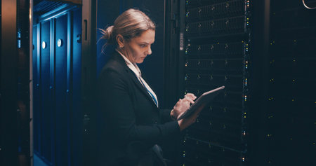 Engineer, woman and typing on tablet in server room for cybersecurity, system backup or update. Data...