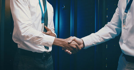 Agreement, meeting and people shaking hands in server room for network administration deal....