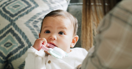 Child, baby girl and chewing toys in living room with mom, home and development or growth and...