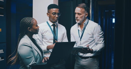 Man, laptop and team with solution in server room with cybersecurity, system or collaboration....