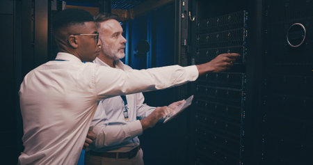 Men, tablet and inspection in server room with maintenance, review and point with mentor for system...