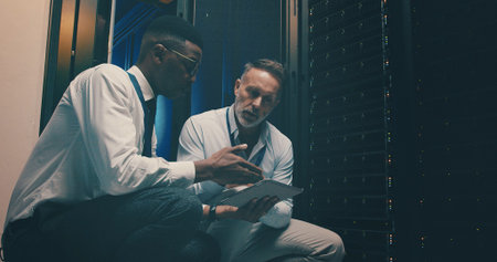 Engineer, men and teamwork with tablet, server room and planning for software upgrade or discussion....