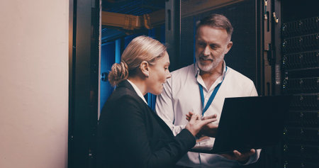 Laptop, discussion and people with in server room for technical support, database or cybersecurity....