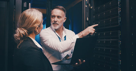 Laptop, pointing and team of engineers in server room for technical support, database or...