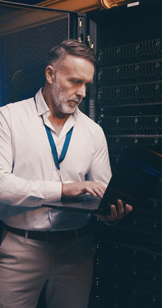 Laptop, typing and technician or man in server room for cyber security, software update and database...
