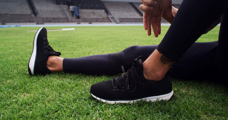 Exercise, hands and shoes with person on grass in stadium for start of competition or tournament....