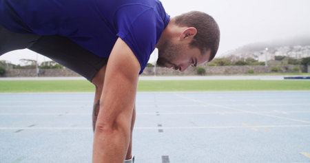 Runner, man and ready at start line on track for running practice, race fitness or cardio at...
