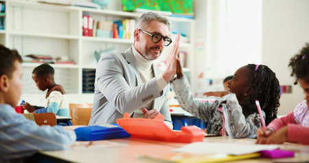 Teacher, girl and high five for motivation in classroom with lesson, support and education at...