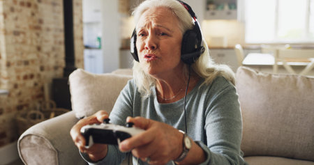 Senior woman, console and playing video games with headphones on sofa for online entertainment....