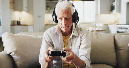 Senior man, console and playing video games with headphones on sofa for online entertainment....