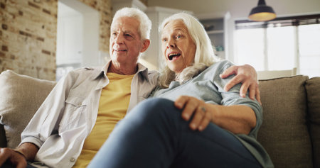 Senior couple, hug and watching tv with surprise on sofa for horror movie, bonding or scary series....