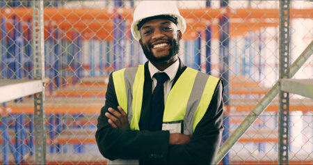 Black man, arms crossed and smile at warehouse, shelves and career in logistics industry at plant....