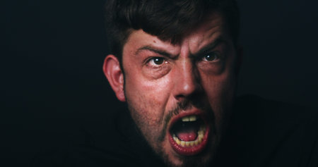 Angry, bipolar and man screaming in studio with schizophrenia, paranoid or panic reaction. Male...