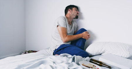 Addiction, man and drugs with alcohol on bed with anxiety, psychosis and loss of appetite. Mockup...