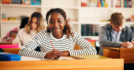 Happy, writing and portrait of girl teenager in classroom for learning, education or development....