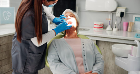 Woman, dentist and torch for mouth exam, check and services for oral care in consultation room....