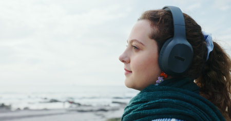 Mindfulness, tourist and woman with headphones, beach or music on vacation, streaming and breathing. Outdoor, space and person with tech for sound, calm and listening to radio on holiday and breakの写真素材