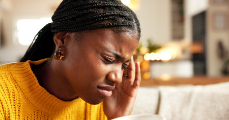 Black woman, headache and pain with stress on sofa for mental health, pressure or vertigo in home....