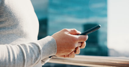 Businessman, hands and typing with phone on balcony for trading account, economy news or research. City, trader and smartphone at office for stock market portfolio, online investment or communicationの写真素材