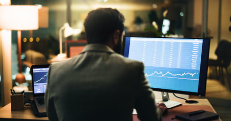 Businessman, back and night trading with computer screen for stock market analysis or research. Man,...