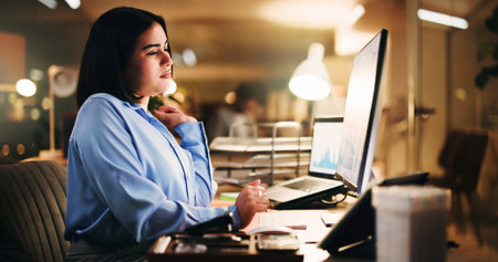 Computer, reading and serious with business woman in office for trading graph, analysis and night. Investment review, overtime and stock broker chart with person for bokeh and problem solvingの写真素材