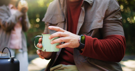 Hands, cup and coffee in forest, camp and rest on hiking trip with partner, outdoor and nature tourism. Person, couple and kettle for tea, drink or warm beverage with break for trekking in woodsの写真素材