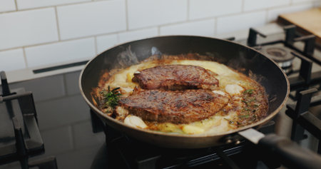 Pan, cooking and steak at restaurant in empty kitchen for gourmet meal, cuisine and process for food. Equipment, stove and meat with sauce, culinary and catering services with interior at dinerの写真素材