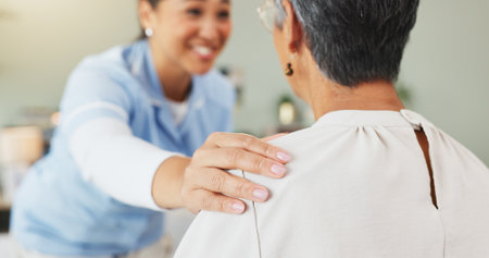 Hands, nurse and comfort old woman at house for support, assurance and good news of diagnosis. Smile, caregiver and senior person for checkup, medical assistance and compassion with healthcare adviceの写真素材