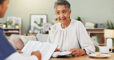 Conversation, senior woman or bible study in home, scripture reading or guidance for new Christian. Teaching, faith lesson or worship leader in house, spiritual bonding or prayer for understandingの写真素材