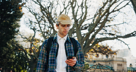 University, outdoor and man with smartphone, student and social media with communication. Campus,...