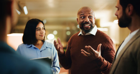 Night, meeting and team of business people in office with tablet, feedback and article ideas or pitch. Creative, media agency and men with woman for brainstorming, news story and planning reportの写真素材