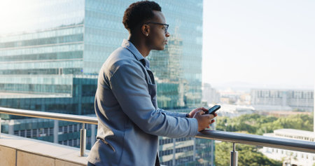 Business, balcony and black man with smartphone, thinking and message to contact, email and urban...