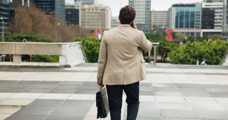 City, commute and phone call with business man from back for travel to job or work location. Buildings, communication and walking with employee person outdoor in urban town for trip to destinationの写真素材