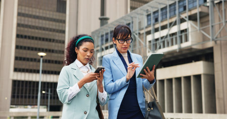 Business women, tablet and walking with personal assistant for schedule or appointments in city. People, boss and planner with technology for notes, agenda or tasks with conversation in New Yorkの写真素材