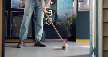 Broom, legs and small business with man in tattoo parlor for preparation or start of work. Cleaning,...